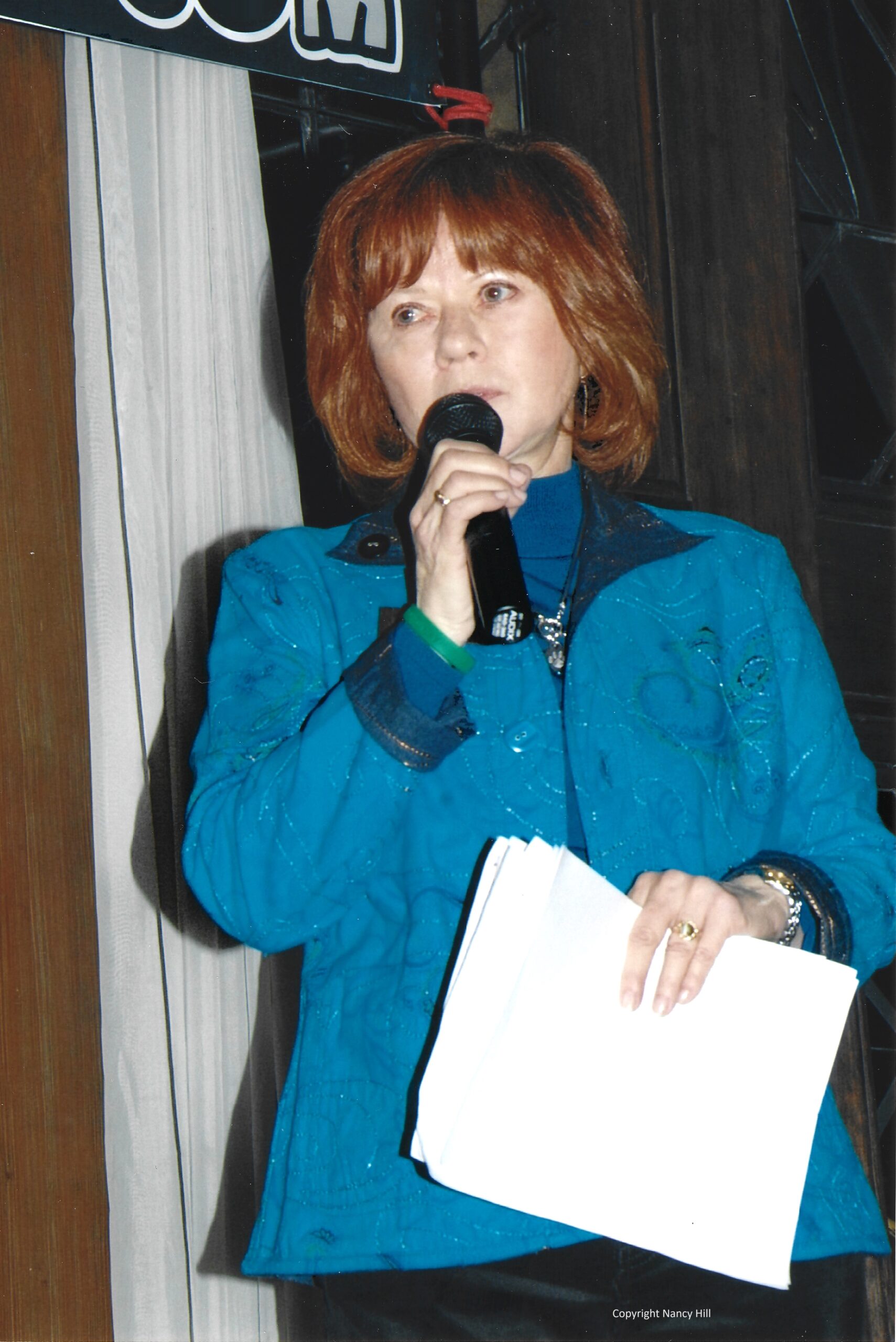 Joan Dalton holding and speaking into a microphone giving a speech to the un-pictured crowd.